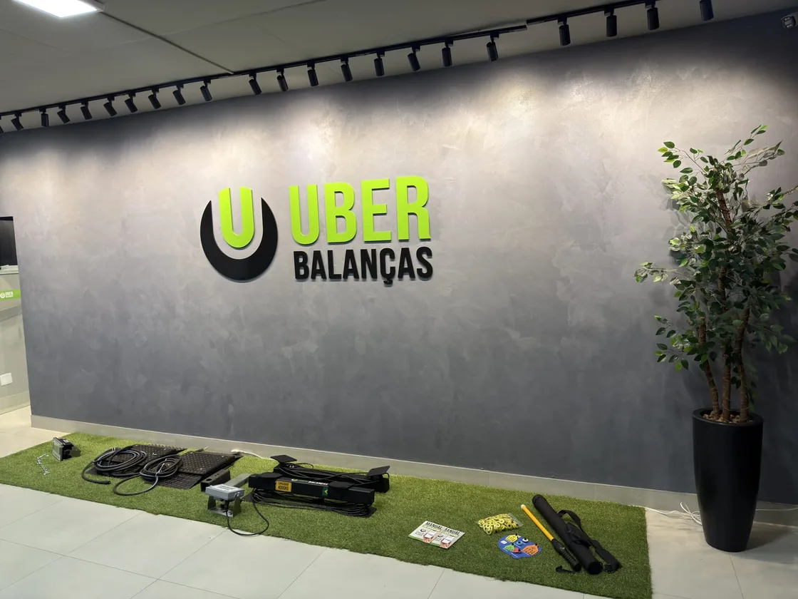 Sede da Uber Balanças em Uberlândia/MG: parede com a marca e balanças eletrônicas fabricadas na empresa